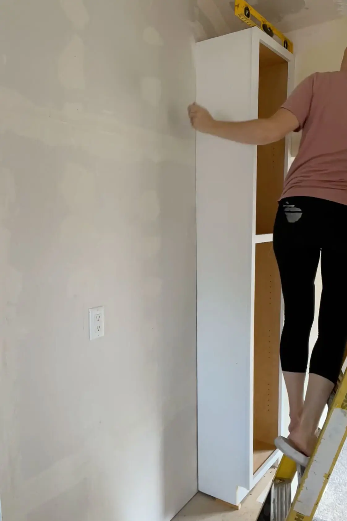 Using shims to level a tall floor cabinet. 